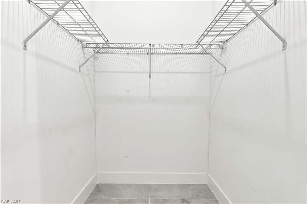 White walls with gray tile flooring and wire shelving