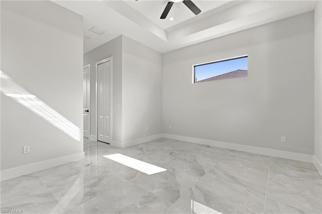 Tray ceiling with a ceiling fan, transom window, and large format tile flooring