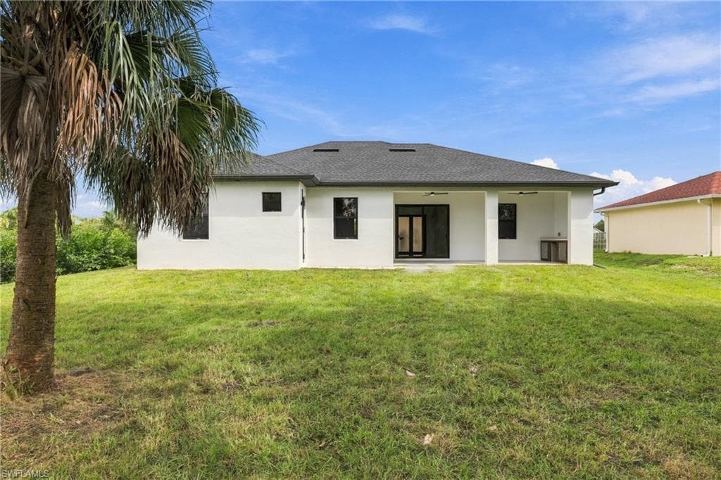 Expansive rear yard with a covered patio featuring two ceiling fans and an outdoor built-in preparation area