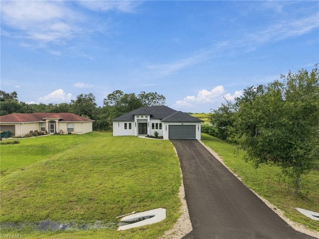Contemporary single-story residence with a dark shingle roof, a paved driveway, and an attached two-car garage