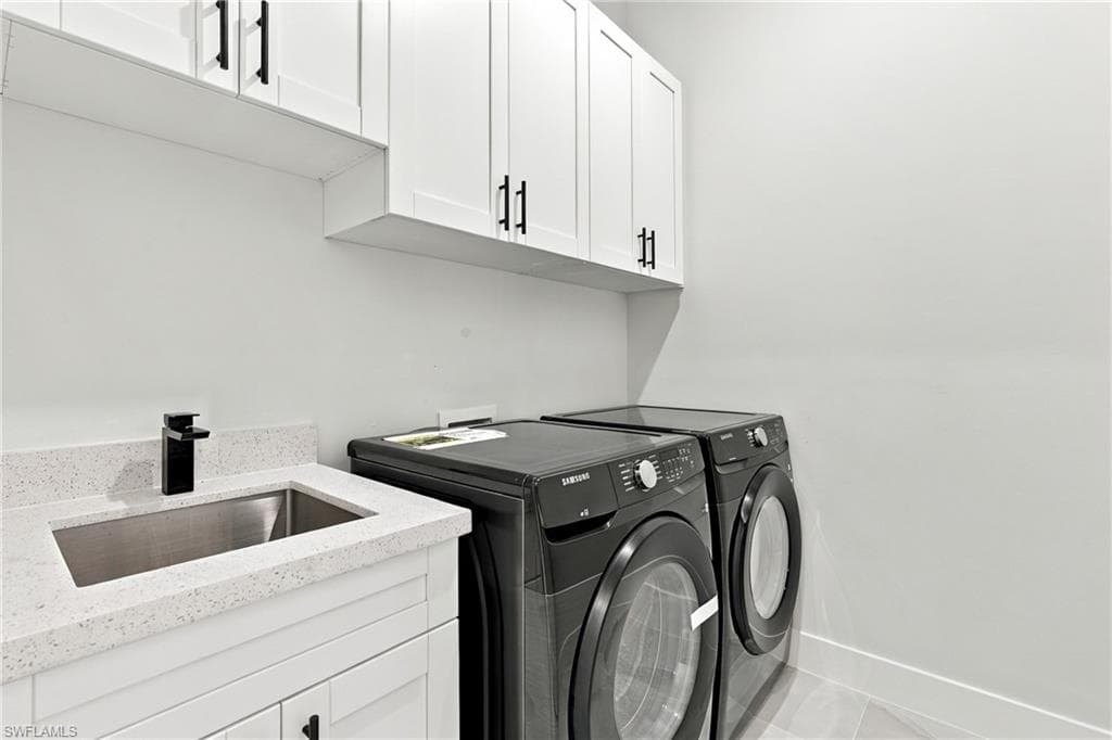 White upper cabinetry with black hardware, under-cabinet lighting, stainless steel sink, black faucet, and white countertop