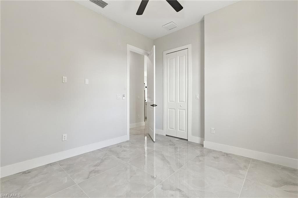 Neutral interior paint, tile flooring, white trim, bifold closet door, and a ceiling fan