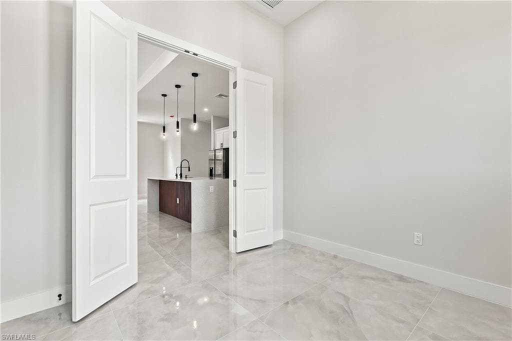 Glossy gray-toned large format tile flooring, white double panel doors, white walls, and recessed lighting