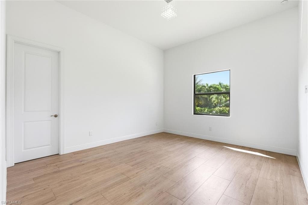 Wood-finish flooring, white walls, white trim, square window, and a white paneled door