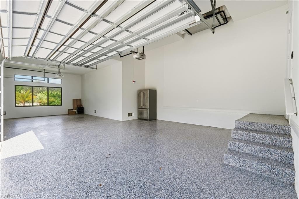 Spacious garage with an epoxy finished floor, multi-pane windows, and three concrete steps
