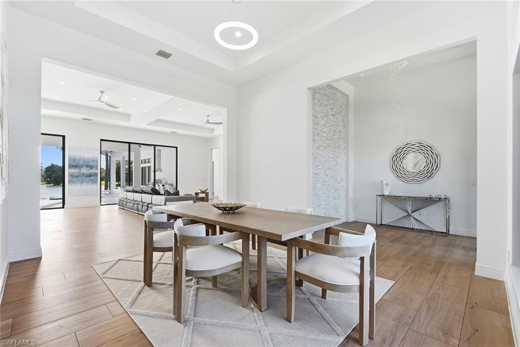 Wood-finish flooring throughout, featuring a recessed ceiling with integrated lighting, and expansive glass sliding doors