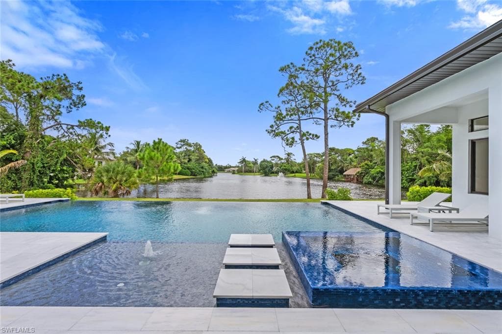 Expansive multi-level pool with integrated water features, a tiled infinity edge, and a wide paver deck