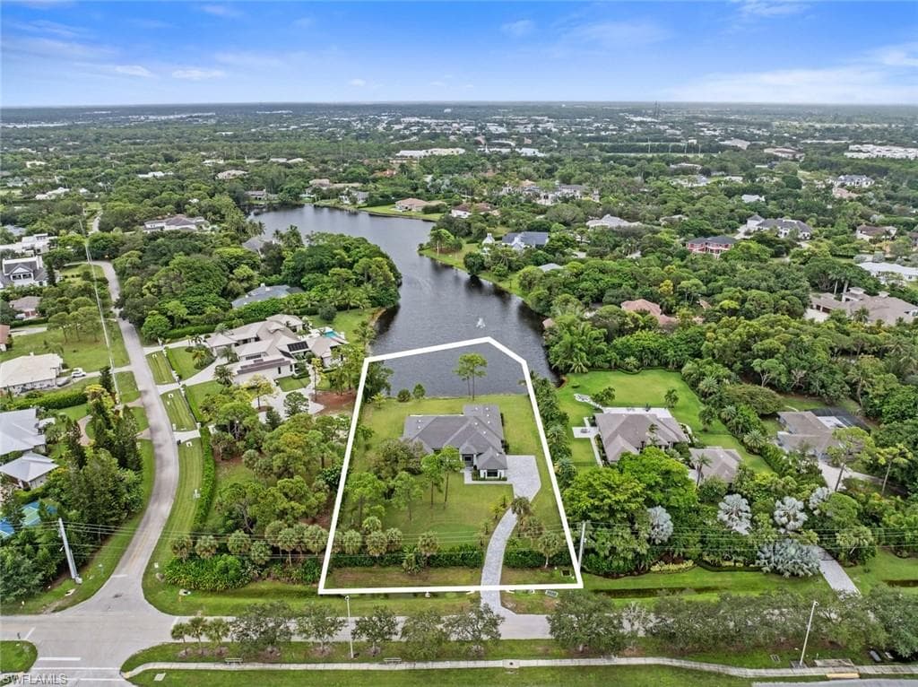 Waterfront property with private water access, mature landscaping, and a curvilinear driveway