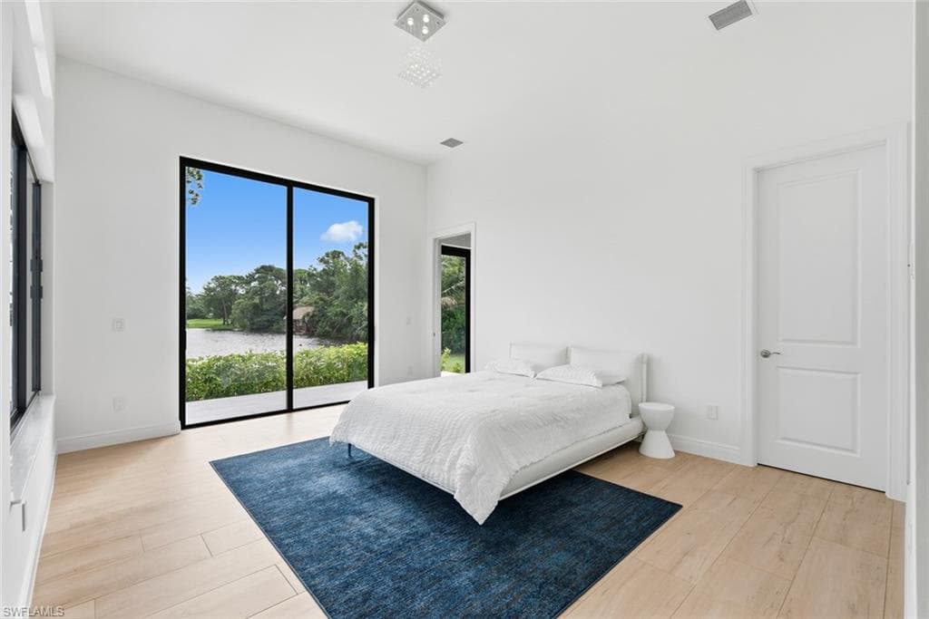Floor-to-ceiling sliding glass doors, light wood-finish flooring, recessed lighting, and a white paneled door