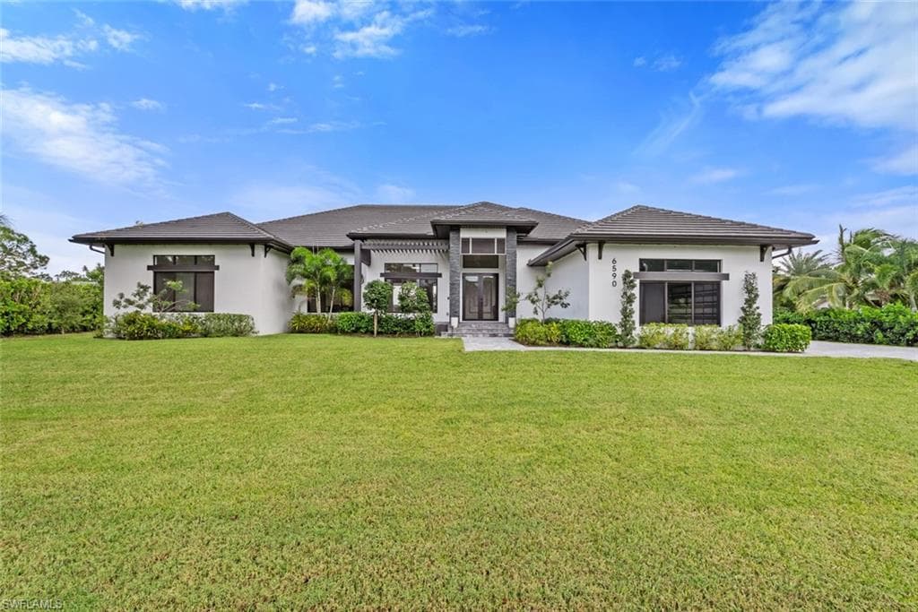 Expansive front lawn with lush landscaping and mature palm trees
